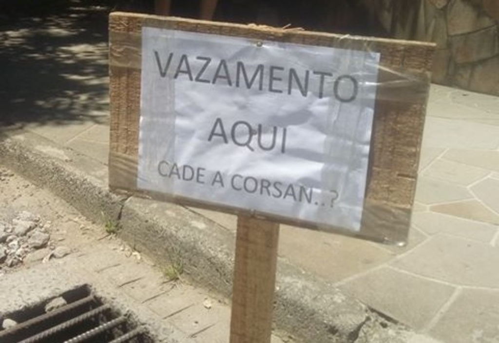 Morador coloca placa em rua para sinalizar vazamento de água