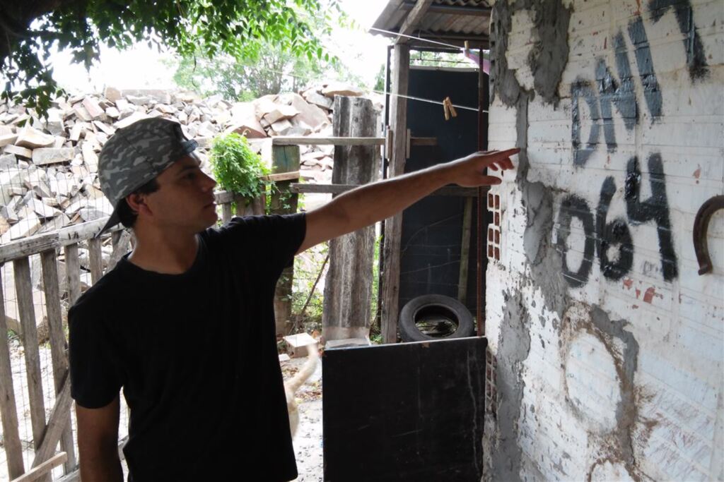 Foto: Deni Zolin - André Palma mostra paredes rachadas devido à trepidação de rolos que fazem aterro do viaduto (ao fundo). Apesar do conserto feito pelo Dnit, ele teme que casa desabe