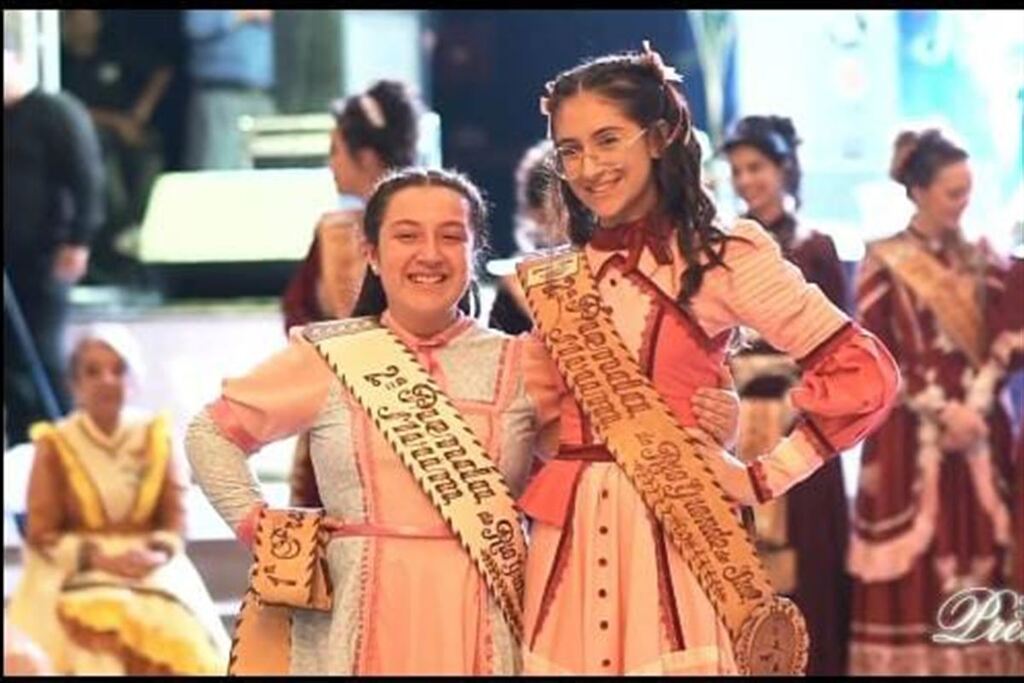 Foto: Divulgação 52ª Ciranda Cultural de Prendas - Giovana (à esq.) recebe a faixa de sua antecessora Dara Montagna Netto, 12ª RT.