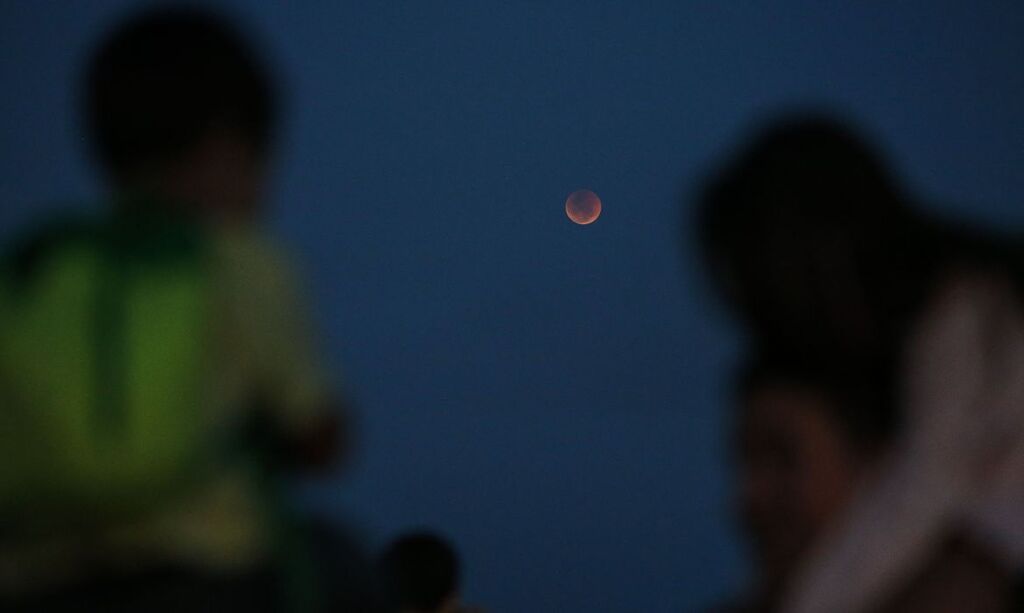 Fernando Frazão/Agência Brasil - Crianças observam o eclipse total da lua, em que o astro ganha tons avermelhados, conhecido como Lua de Sangue, no Forte de Copacabana.