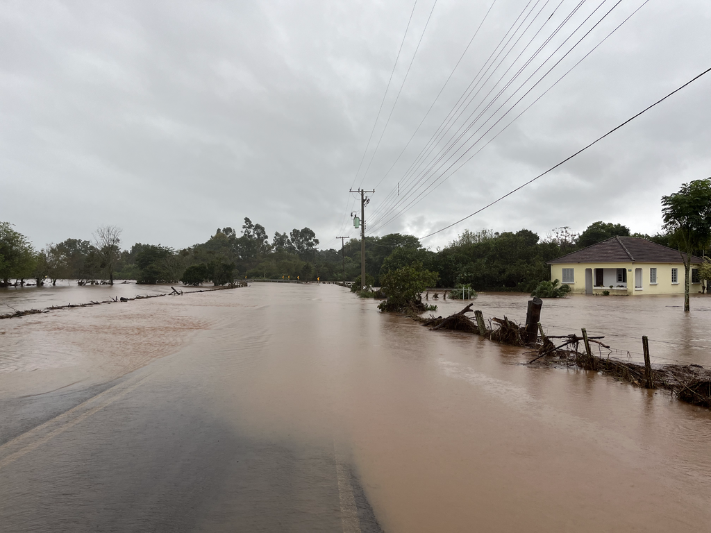 Em Arroio Grande, pista fica submersa e moradores começam a retirar água da chuva com baldes de dentro de residências