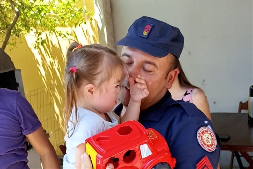Foto: Coro de Bombeiros (Divulgação) - A pequena Luiza nos braços do sargento Joaquim, durante visitar realizada no domingo (17)
